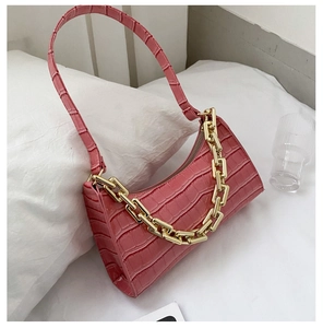 Detailed close-up of pink crocodile-embossed leather bag with chunky gold metal chain