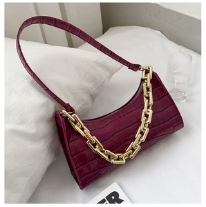 Detail of deep purple faux leather bag featuring crocodile texture and a chunky gold chain