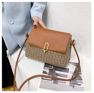 Close-up of houndstooth fabric crossbody bag with brown leather flap and gold clasp
