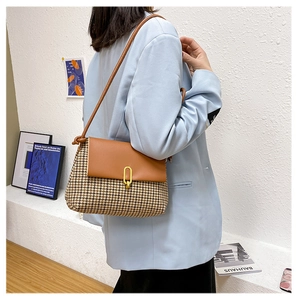 Detail of vintage houndstooth fabric shoulder bag with brown leather flap and metal lock