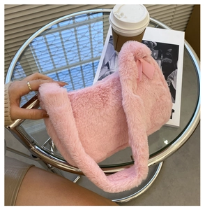 Detail of pink plush shoulder bag with a bow on glass table with cafe accessories