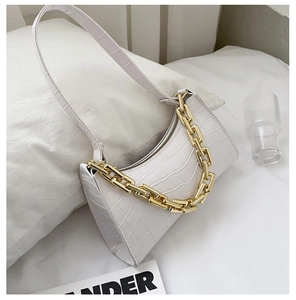 Close-up of white crocodile pattern faux leather shoulder bag with gold chain decor