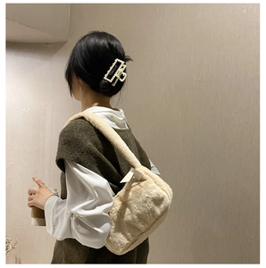 Detail of off-white faux fur shoulder bag with elegant pearl hair clip accessory