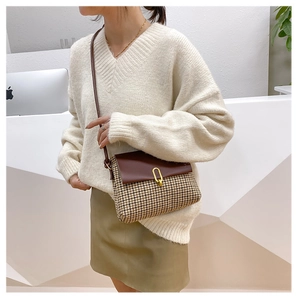 Detail of crossbody bag with houndstooth fabric, brown leather flap and metal ring buckle
