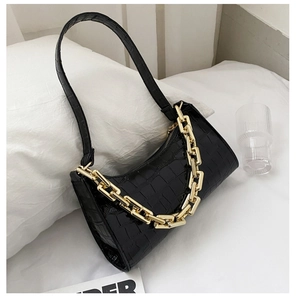 Detail of black crocodile texture faux leather bag with chunky gold chain hardware