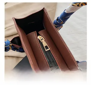 Detail of brown leather tote bag with gold zipper and stylish blue silk scarf wrap handle