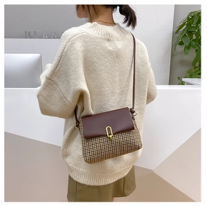 Detail view of retro plaid crossbody bag with brown leather flap and golden buckle