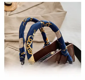 Detailed shot of dark brown quilted handbag with elegant blue patterned scarf handle wrap