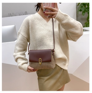 Detail of vintage houndstooth crossbody bag with brown leather flap and golden U-shaped clasp