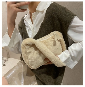 Detailed close-up of a soft cream plush shoulder bag with smooth zipper and leather puller