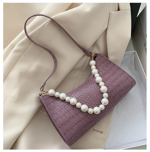 Macro view of purple crocodile texture underarm bag with pearl strap and gold hardware