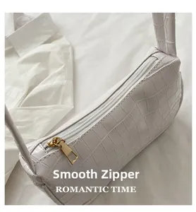 Detail of smooth gold zipper on white crocodile pattern baguette shoulder bag