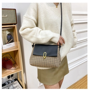 Close-up of vintage houndstooth crossbody bag with black leather flap and gold metal clasp