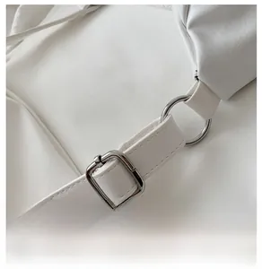 Détail de la bandoulière réglable en cuir blanc et boucle argentée d'un sac élégant