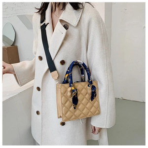 Detail of beige quilted crossbody bag featuring silk scarf handle and wide canvas strap