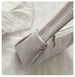 Detailed view of crocodile embossed leather and precise stitching on an off-white bag