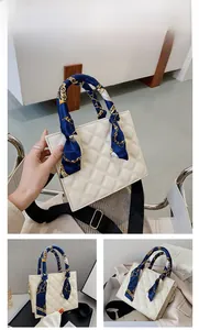 Close-up of a white quilted crossbody bag with blue floral scarf handle decoration