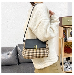 Detail of crossbody bag with houndstooth fabric, black leather flap and gold metal clasp
