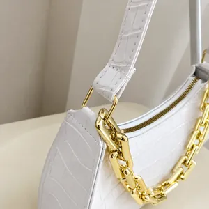 Detail of white crocodile embossed baguette bag with chunky gold chain strap and metal buckle