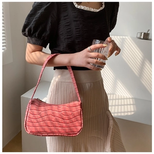 Detailed close-up of a pink crocodile texture baguette shoulder bag with zipper detail