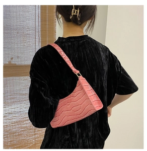 Bolso rosa con textura de cocodrilo mostrado en el hombro para ver el tamaño real