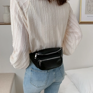Sac banane tendance en similicuir noir avec double fermeture éclair porté par un mannequin