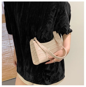 Detalle de bolso rosa con efecto cocodrilo llevado con un top de terciopelo negro