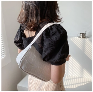 Detail of white crocodile pattern crescent underarm bag with refined faux leather texture