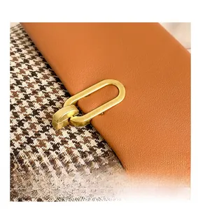 Detailed macro view of golden metal lock on houndstooth fabric and brown leather bag