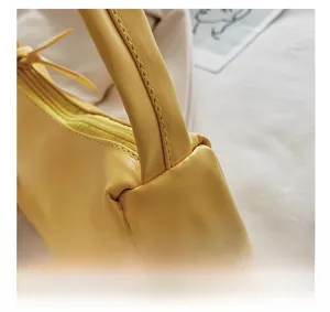 Detailed close-up of reinforced shoulder strap stitching on yellow PU leather baguette bag