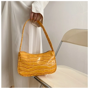 Close-up of bright orange faux crocodile leather baguette bag with glossy finish and zipper