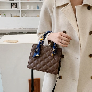 Brown quilted crossbody bag with silk scarf handle on model in minimalist setting