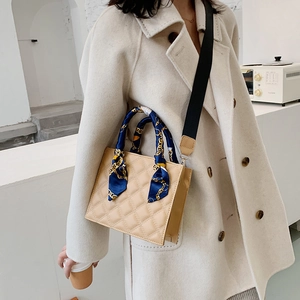 Chic beige quilted square handbag with silk scarf handle and wide black shoulder strap