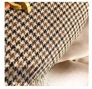 Close-up of vintage houndstooth fabric with gold metal lock and brown leather strap