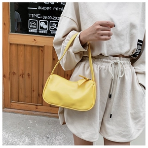 Detail view of bright yellow mini baguette bag with smooth faux leather finish