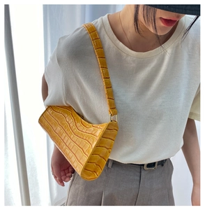 Vista detallada del bolso de hombro amarillo con patrón de cocodrilo en modelo