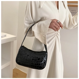 Detail of black crocodile texture shoulder bag on a white dress model outfit