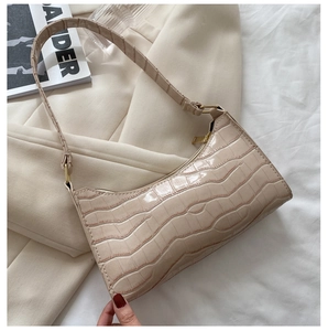Detalle de la textura de cocodrilo beige y la correa ajustable del bolso de hombro
