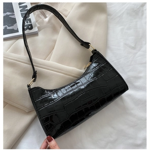 Detalle de bolso de axila negro con textura de cocodrilo y herrajes dorados en blazer