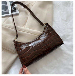 Detalle de bolso de hombro marrón efecto cocodrilo sobre blazer beige con revista