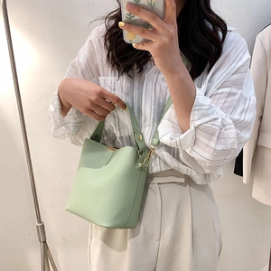 Minimalist mint green bucket bag with top handle and adjustable shoulder strap