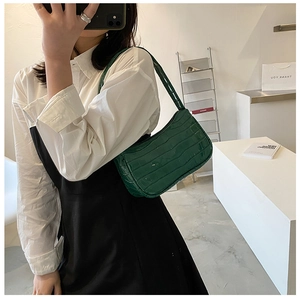 Detailed view of the emerald green baguette bag with glossy crocodile texture finish