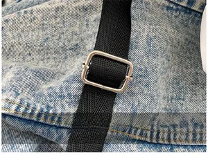 Detail of adjustable black nylon shoulder strap with silver metal buckle on denim bag