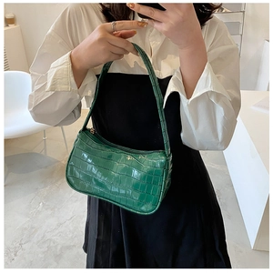 Detail of vintage green crocodile pattern baguette bag worn as a shoulder piece