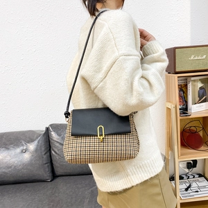 Retro houndstooth crossbody bag with leather flap and gold U-shaped buckle on a model