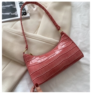 Detalle de textura de cocodrilo rosa y herrajes dorados en bolso de hombro