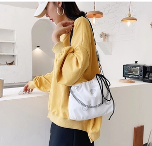 Detail view of a white canvas bucket bag with gray butterfly print and chunky chain strap