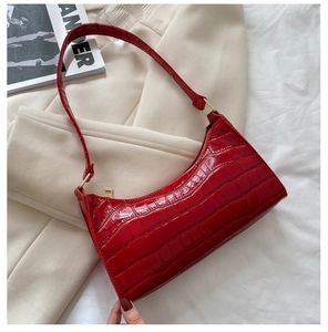 Detalle del bolso de hombro rojo con estampado de cocodrilo, brillo y cadena dorada