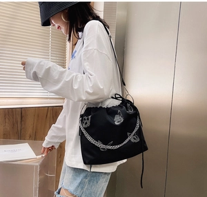 Detail of black drawstring bucket bag with white butterfly prints and silver chain strap