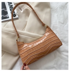 Bolso de axila marrón caramelo con patrón de cocodrilo sobre blazer beige